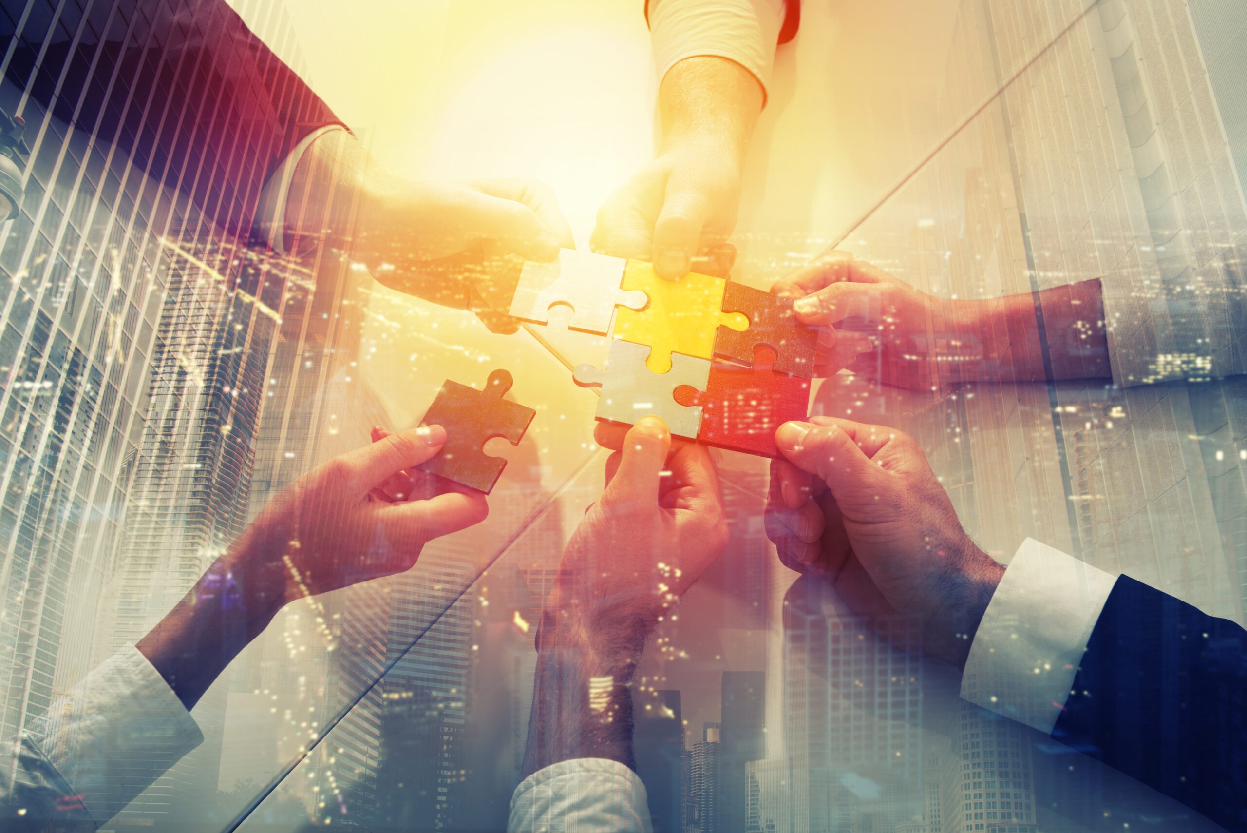 Hands holding colorful puzzle pieces, symbolizing teamwork and collaboration in a business context